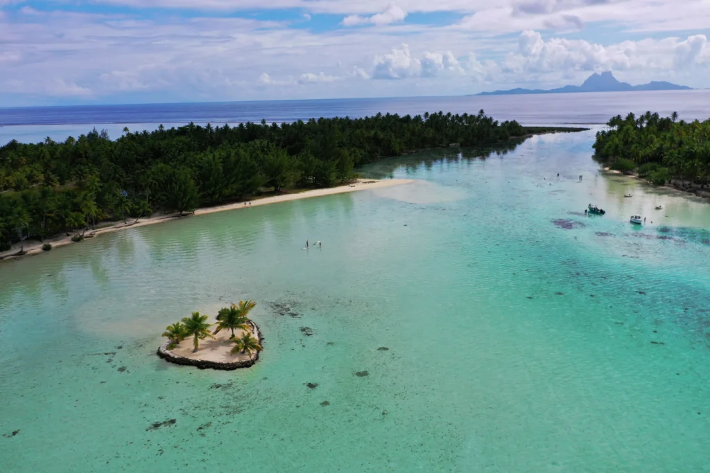 Lagon vu du ciel avec passe étroite et faible profondeur, typique des zones à naviguer en voilier ou catamaran.